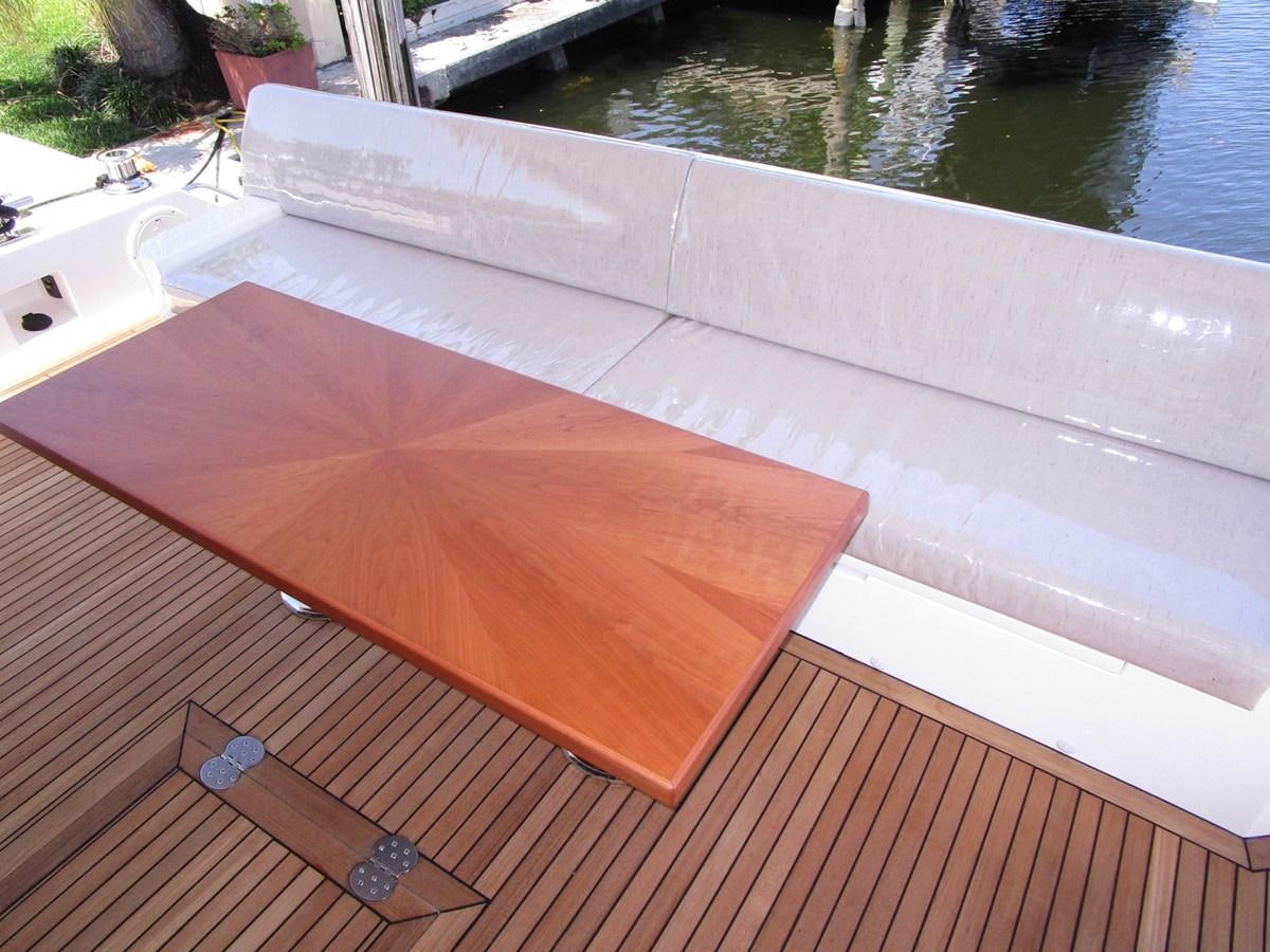 a deck with a wood railing and a body of water in the background aboard JOHNSON 83 SKYLOUNGE Yacht for Sale