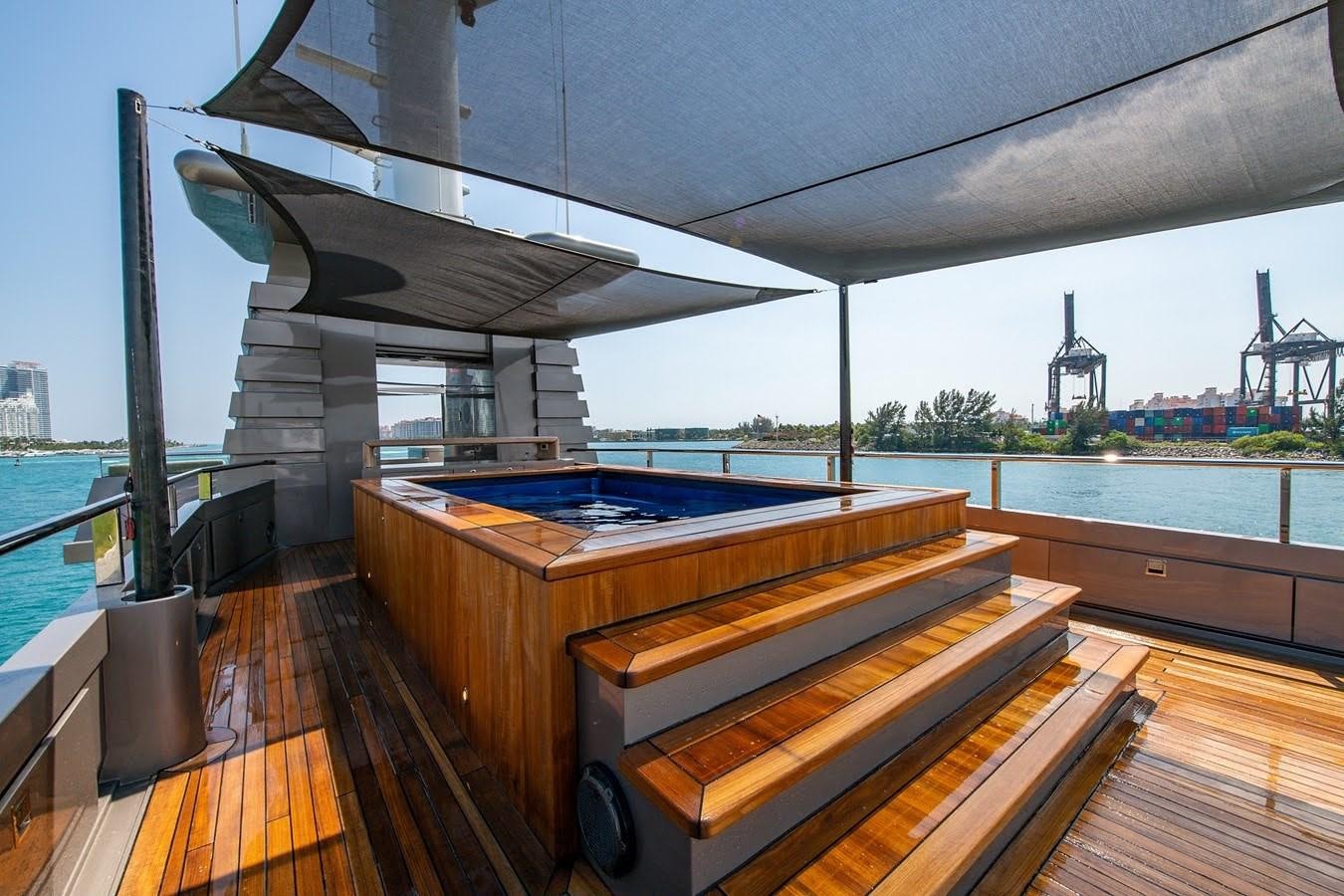 a deck with a large pool and a large building in the background aboard MIZU Yacht for Sale