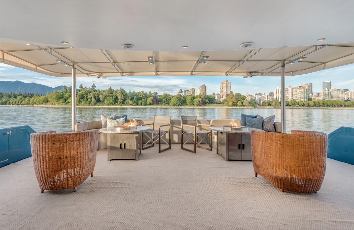 a group of chairs under a covered area with a city in the background aboard ASCENTE Yacht for Sale