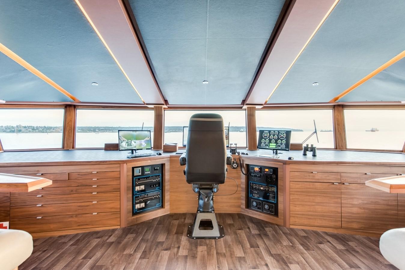 a room with a large window and a large wood cabinet with a black stove and a wood floor aboard ASCENTE Yacht for Sale