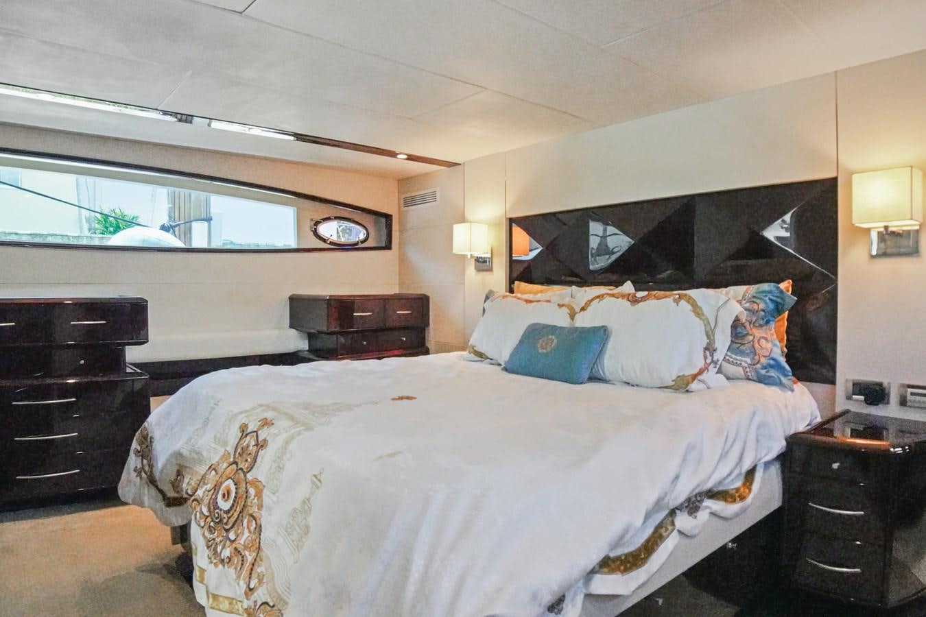 a bedroom with a bed and a window aboard LAZZARA 68' Yacht for Sale
