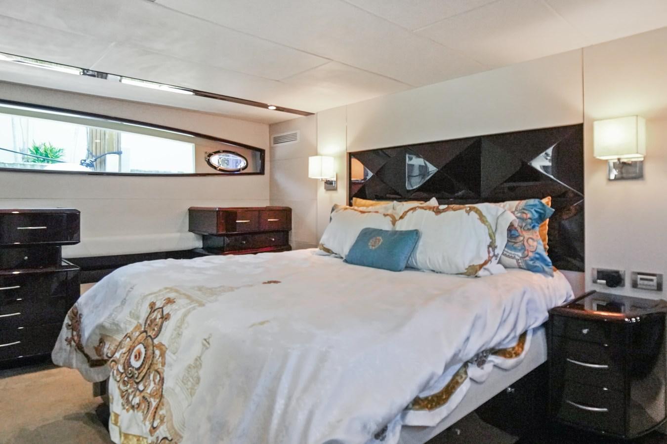 a bedroom with a bed and a dresser aboard LAZZARA 68' Yacht for Sale