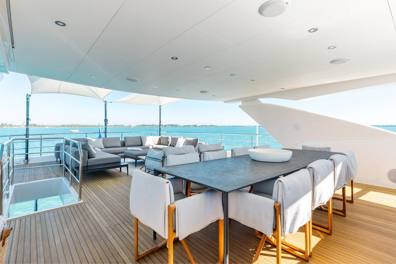 a large room with a table and chairs and a large pool aboard ADAGIO Yacht for Sale