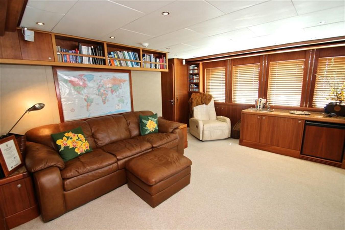 a living room with a couch and a book shelf aboard IMPETUS Yacht for Sale