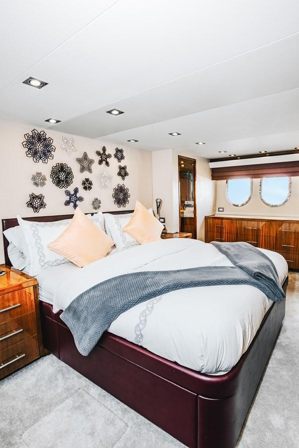 a bedroom with a bed and a dresser aboard HATTERAS 105 Yacht for Sale