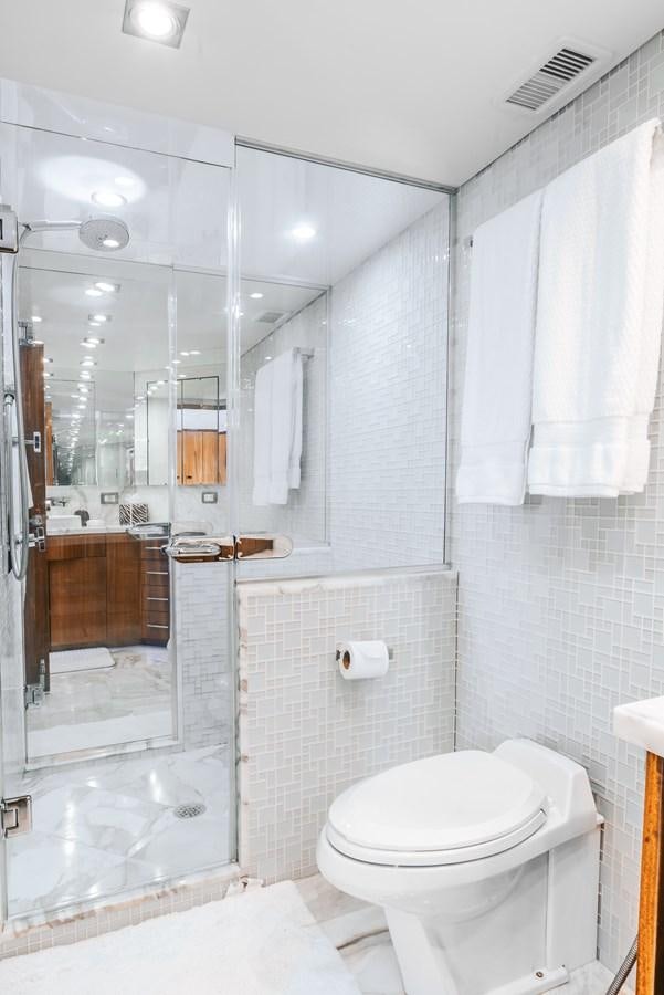 a bathroom with a glass shower aboard HATTERAS 105 Yacht for Sale