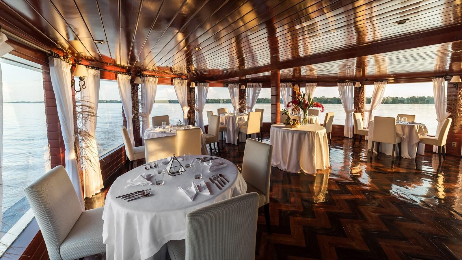 a room with tables and chairs aboard CRUCERO AMAZONAS Yacht for Sale