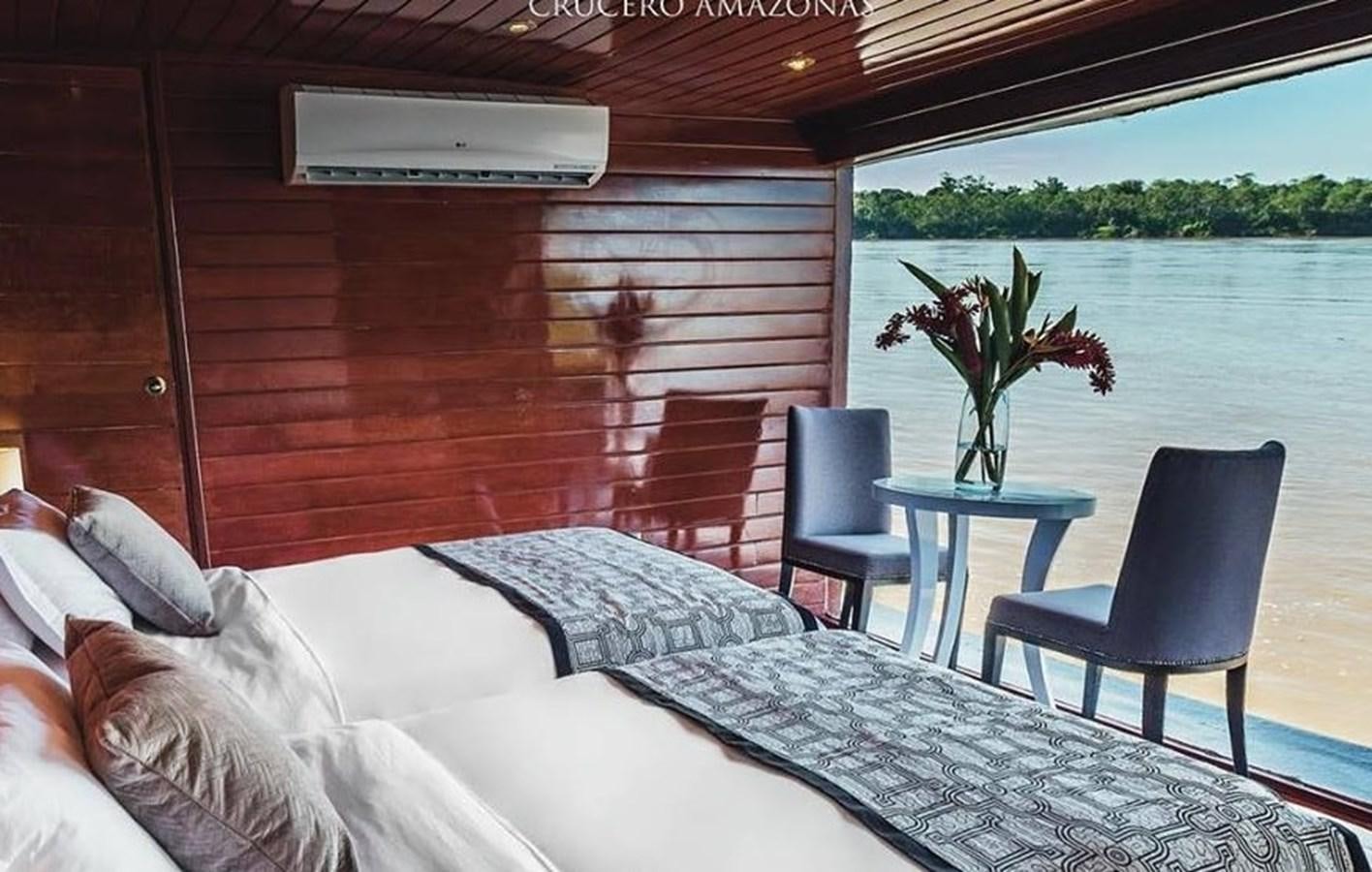 a bed and a table in a boat aboard CRUCERO AMAZONAS Yacht for Sale