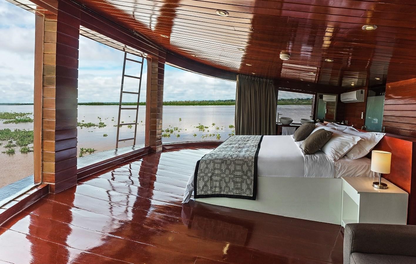 a room with a bed and a window aboard CRUCERO AMAZONAS Yacht for Sale