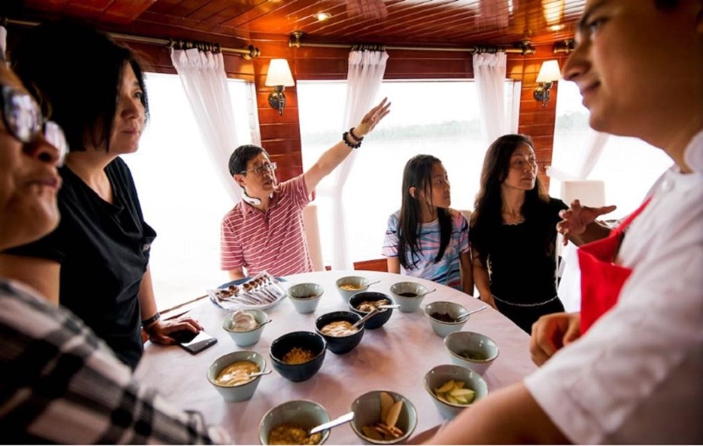 a group of people sitting around a table with food and drinks aboard CRUCERO AMAZONAS Yacht for Sale