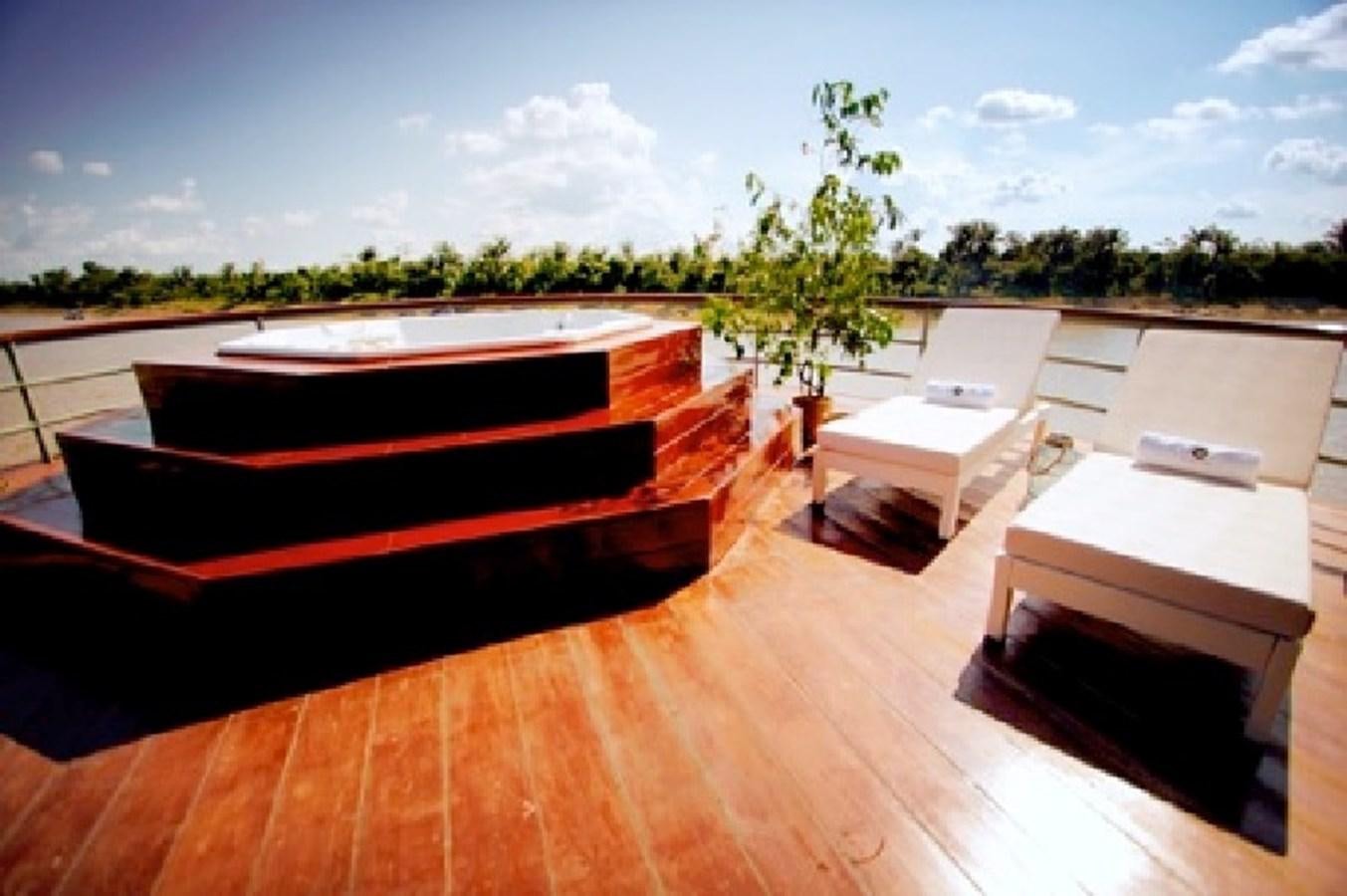 a deck with a pool and trees in the background aboard CRUCERO AMAZONAS Yacht for Sale