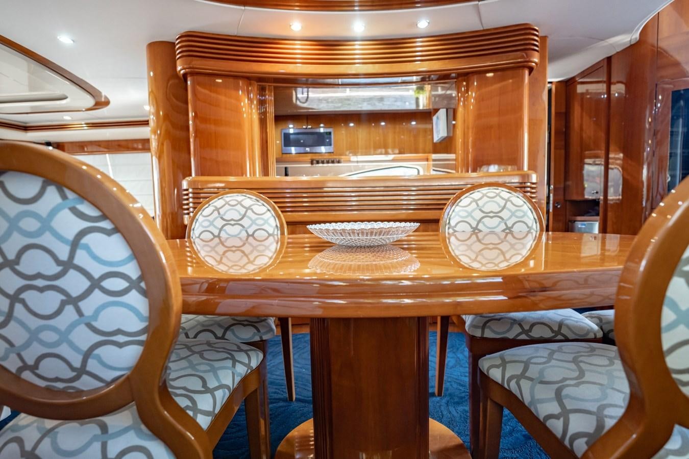 a table with chairs and a wood cabinet aboard GET WET Yacht for Sale