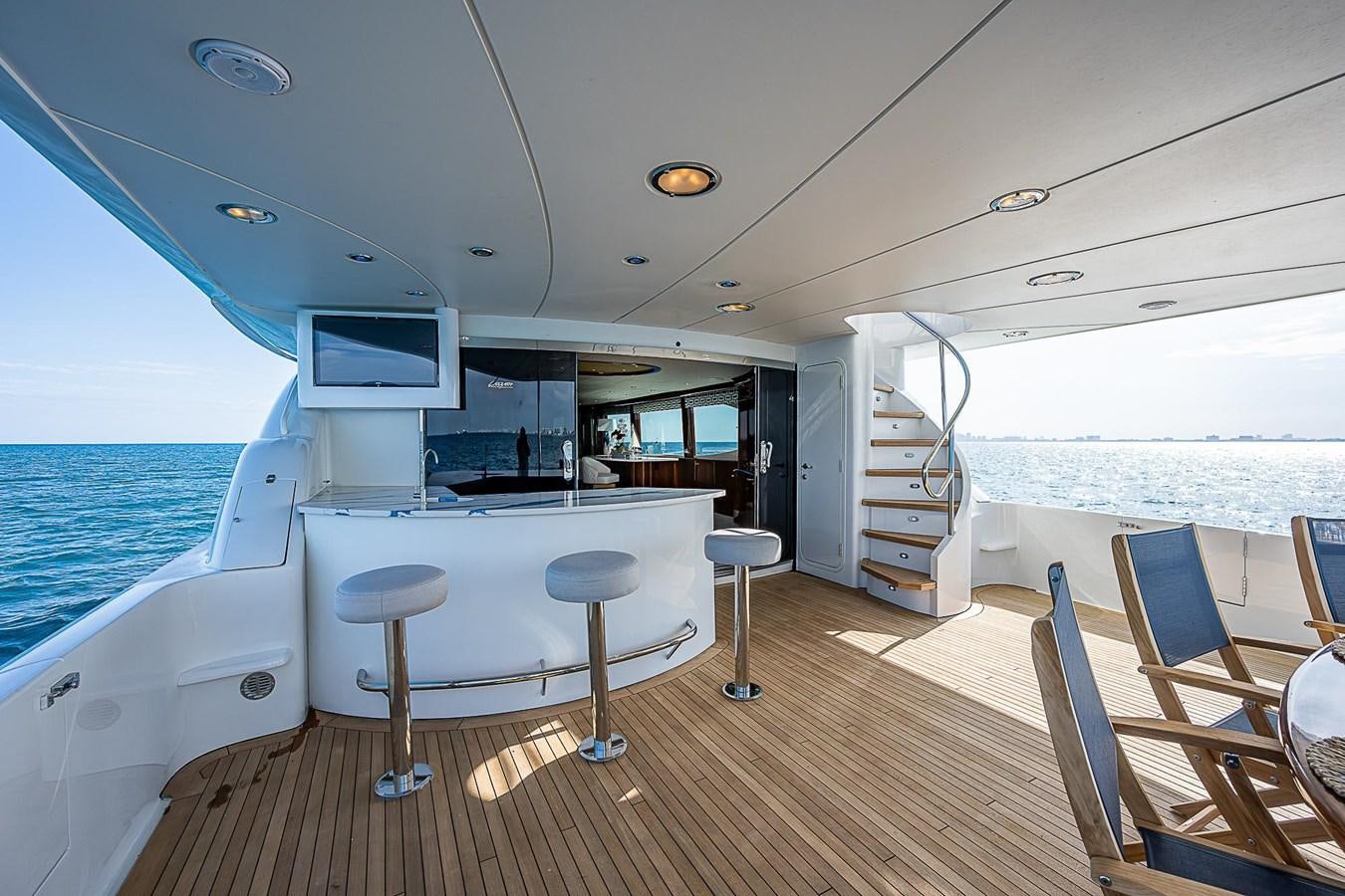 a boat with stools and a table and chairs on a deck aboard LAZZARA 116 OPEN BRIDGE Yacht for Sale
