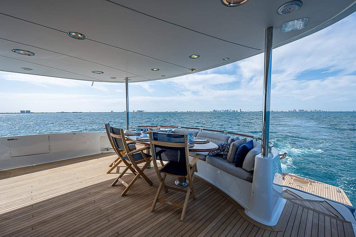 a table and chairs on a deck overlooking the ocean aboard LAZZARA 116 OPEN BRIDGE Yacht for Sale