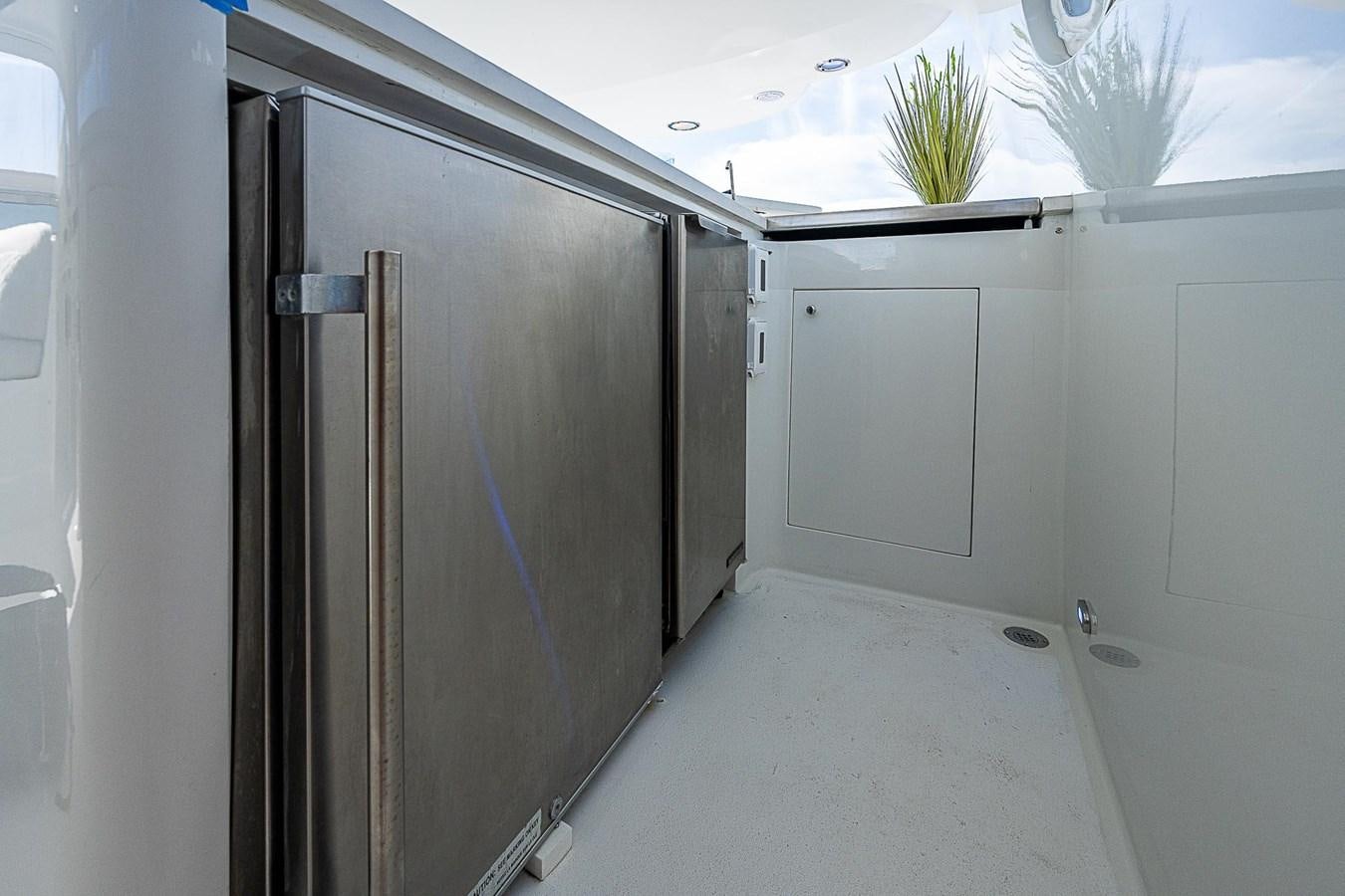 a room with a refrigerator and cabinets aboard LAZZARA 116 OPEN BRIDGE Yacht for Sale