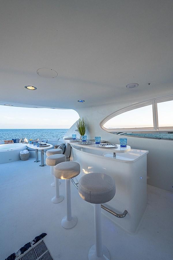 a white kitchen with stools aboard LAZZARA 116 OPEN BRIDGE Yacht for Sale