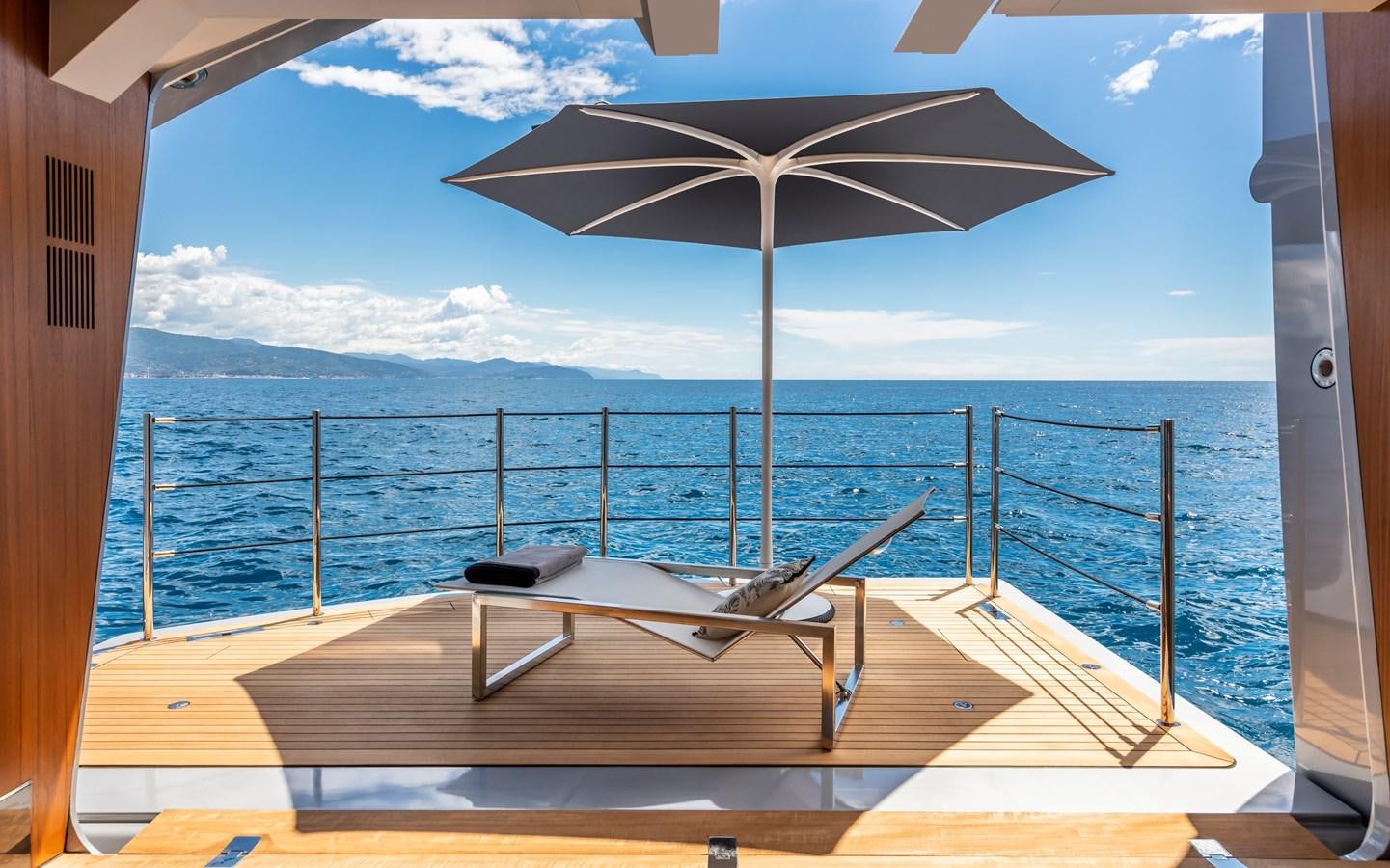 a deck with a large umbrella on it and a body of water in the background aboard CHORUSLINE Yacht for Sale
