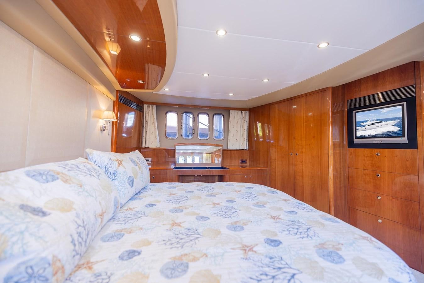 a bed with a blue and white comforter and a wood cabinet aboard COOL BREEZE Yacht for Sale