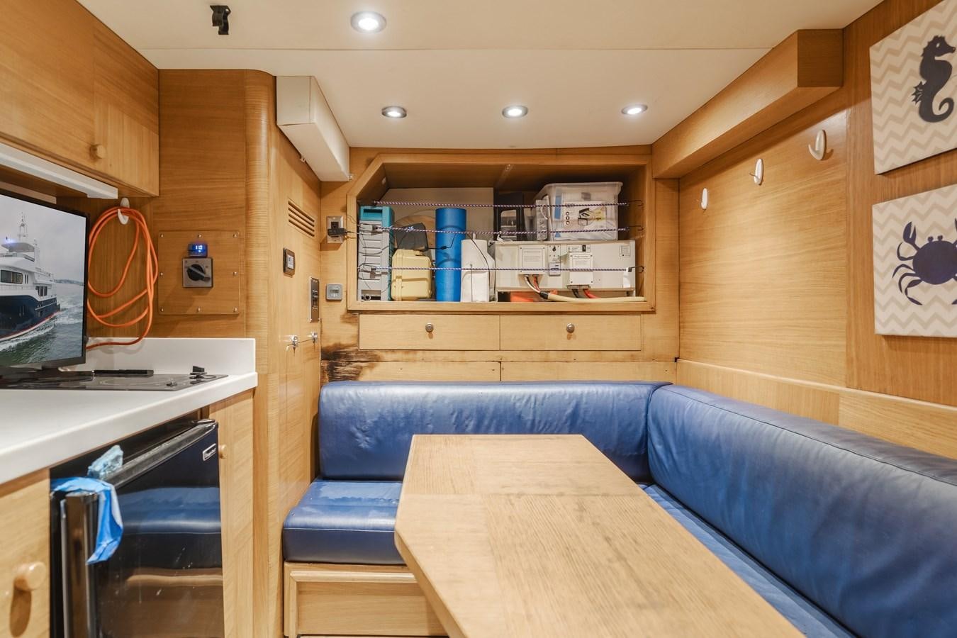 a wood paneled kitchen with a blue couch and a wood table aboard UNDAUNTED Yacht for Sale