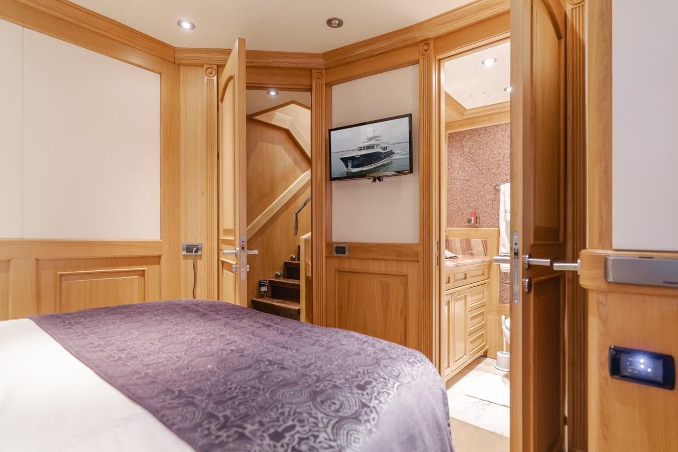 a bedroom with a bed and a television on the wall aboard UNDAUNTED Yacht for Sale