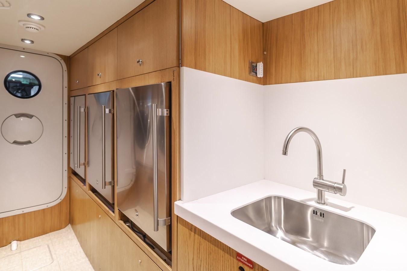 a kitchen with a sink and refrigerator aboard UNDAUNTED Yacht for Sale