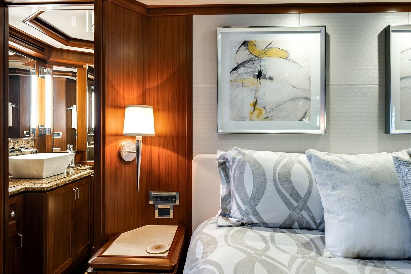 a bed with a white pillow and a painting on the wall aboard UNCORKED Yacht for Sale