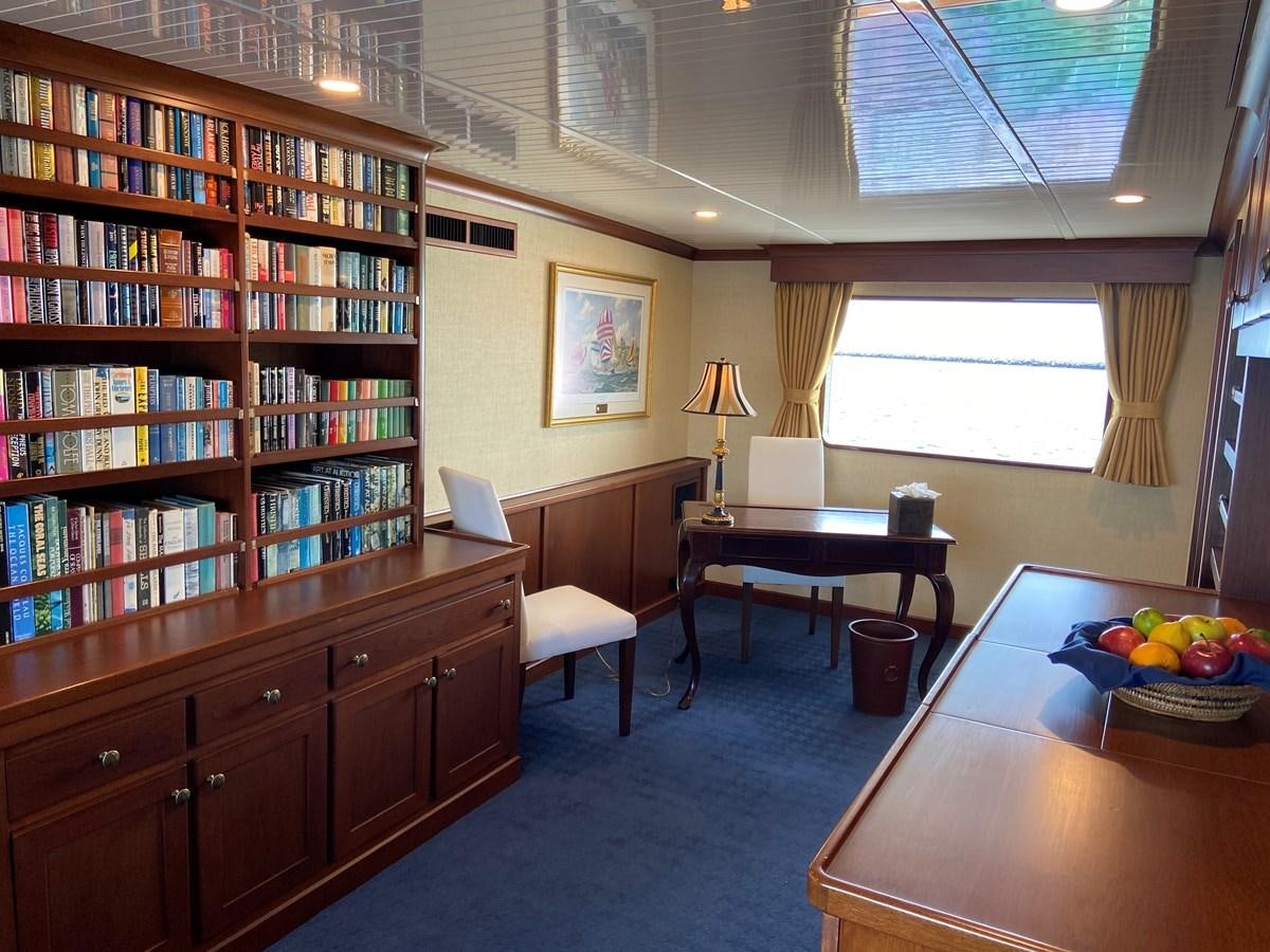 a room with a table and bookshelves aboard BUCKPASSER Yacht for Sale