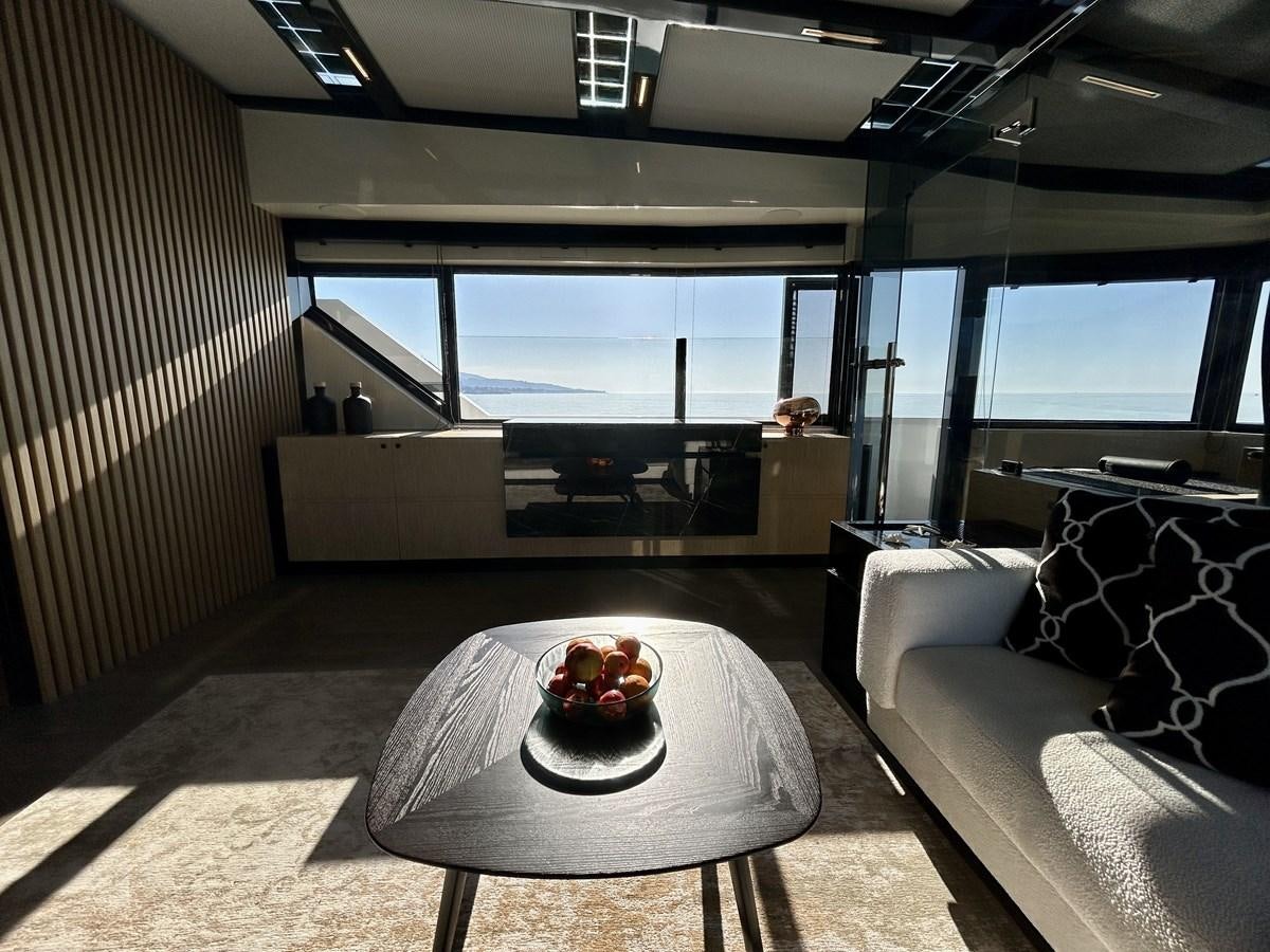 a room with a couch and a table with a view of the ocean aboard SHERPA 80 Yacht for Sale
