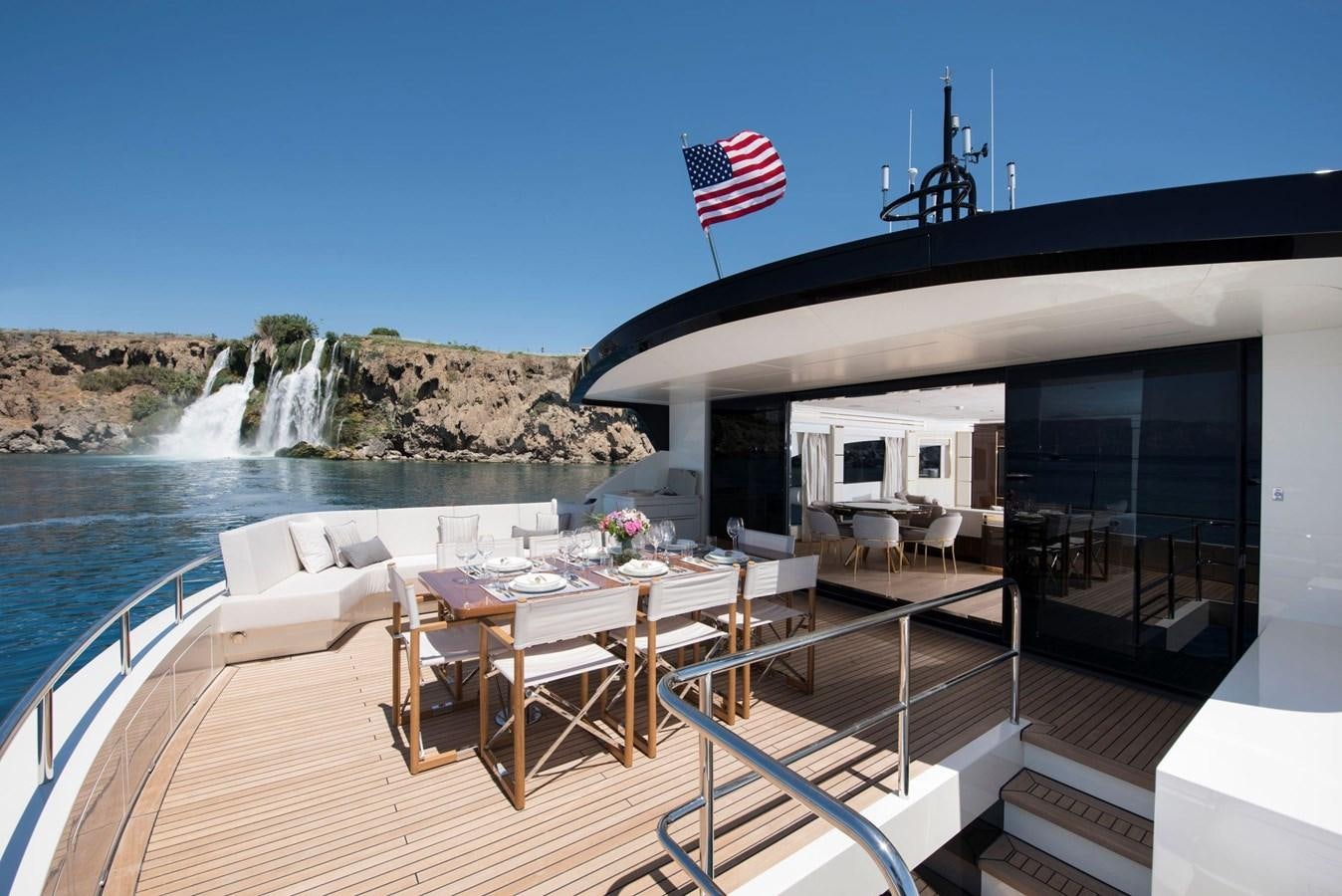 a deck with a table and chairs on it and a body of water in the background aboard SANDRO Yacht for Sale