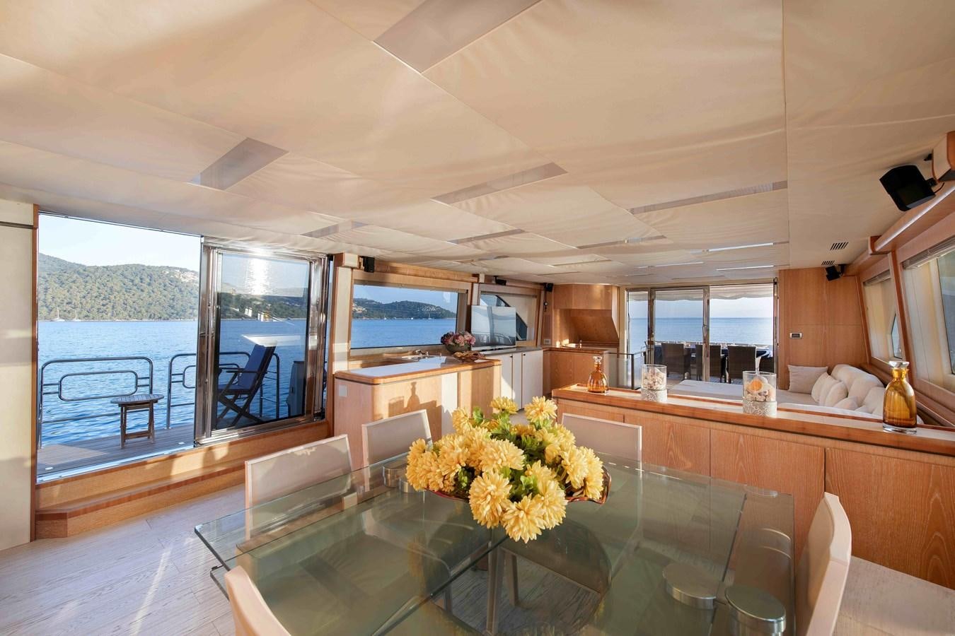 a large kitchen with a large glass table and a view of the ocean aboard ANDIAMO Yacht for Sale