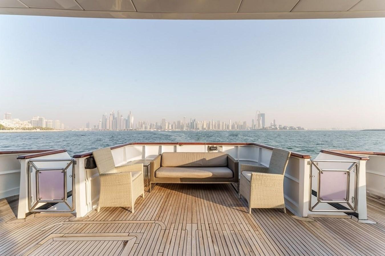 a deck with chairs and a city in the background aboard ALIA 7 Yacht for Sale