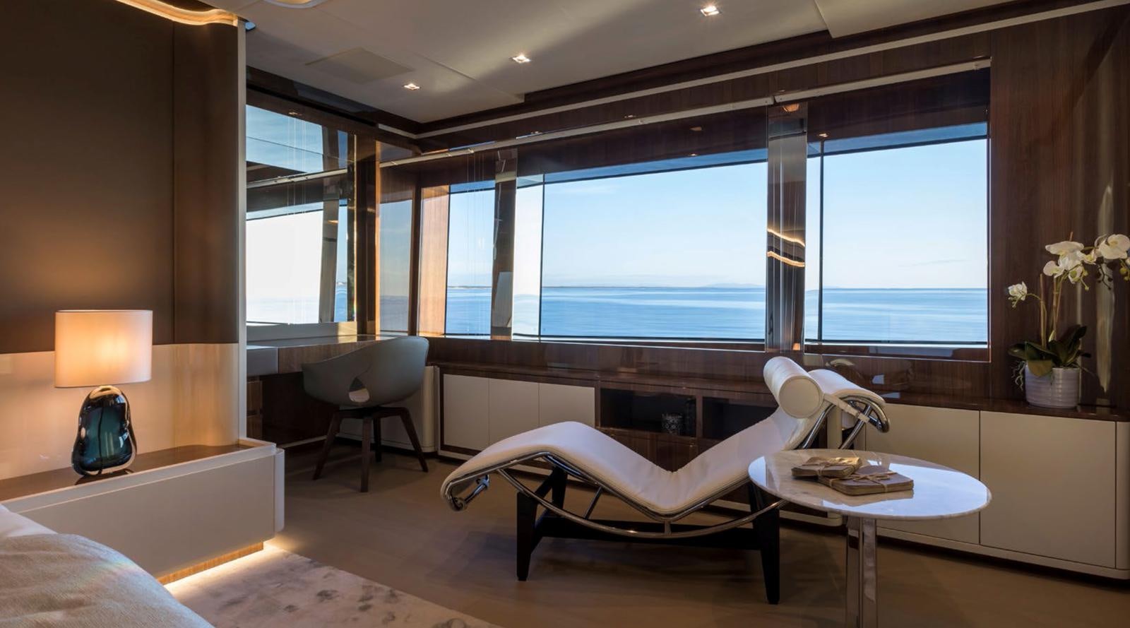 a room with a large window and a desk with a chair and a table with a lamp and aboard GOLDENEYE Yacht for Sale