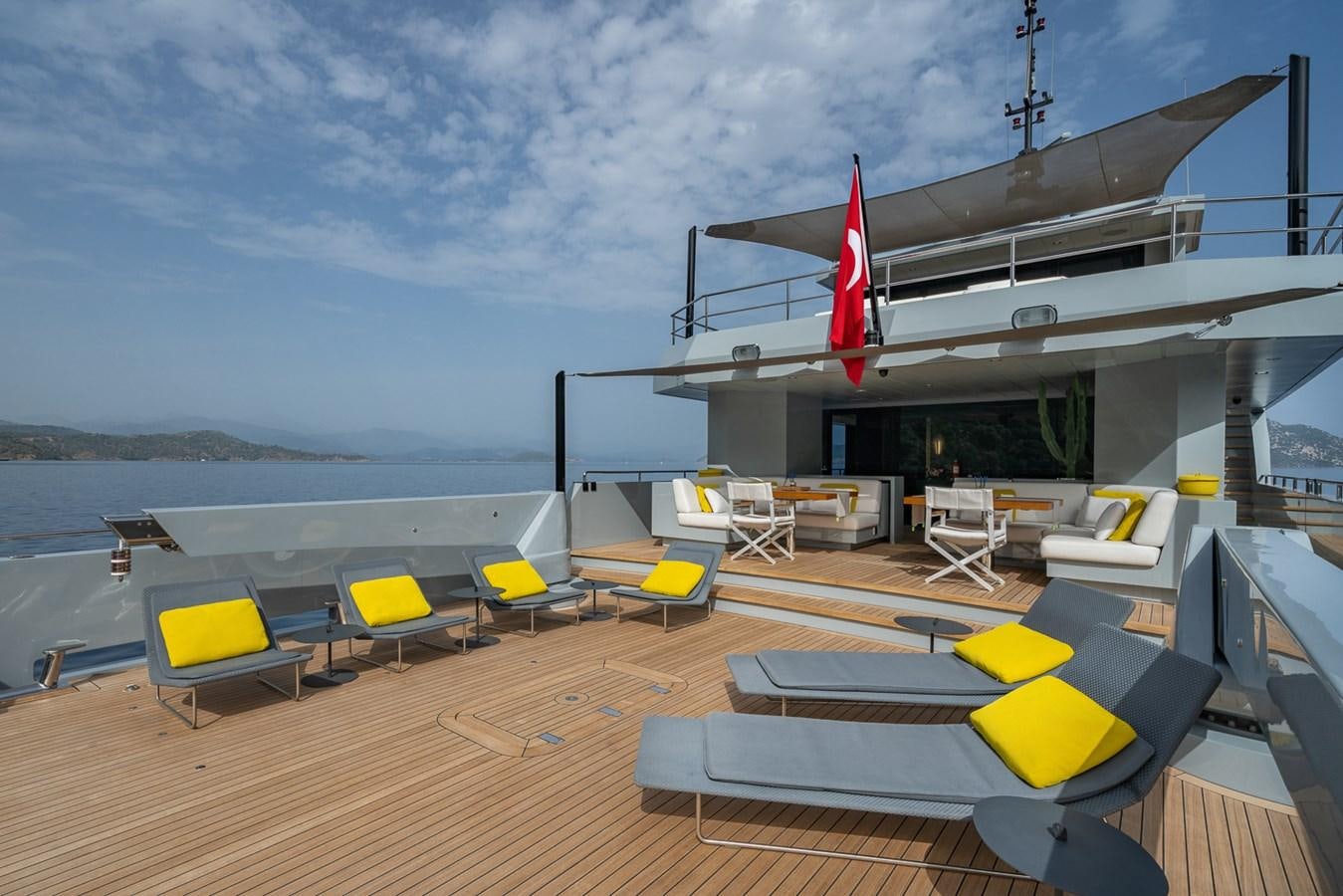 a deck with tables and chairs on it by the water aboard ESOSH Yacht for Sale