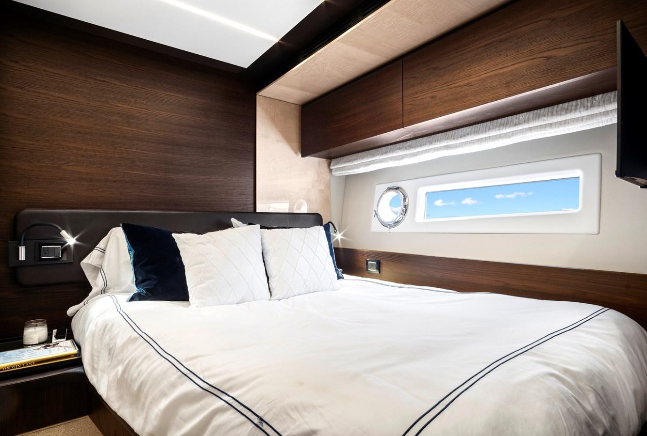 a bed with a white sheet and a television on the wall aboard GRATITUDE Yacht for Sale