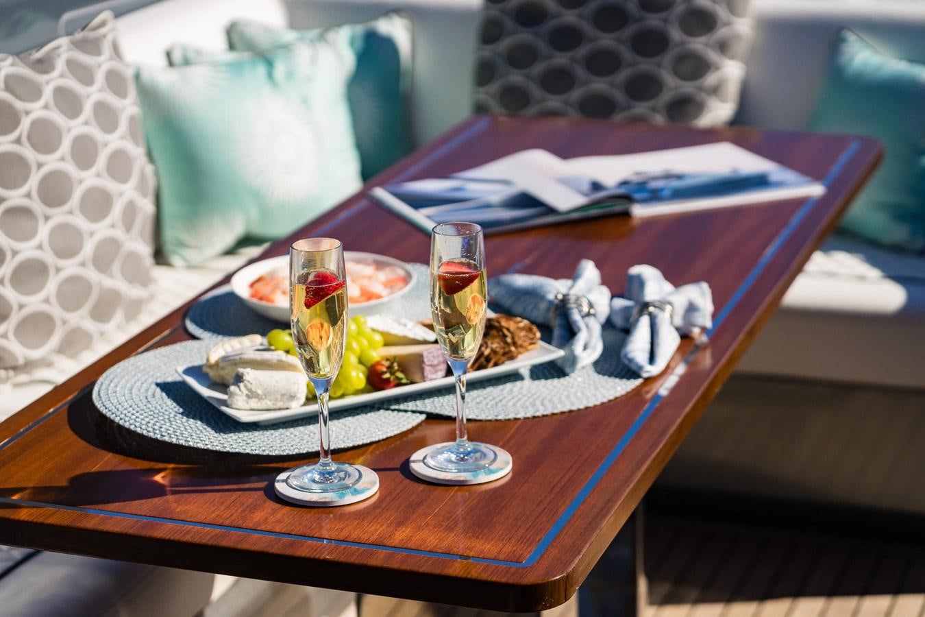 a table with a plate of food and glasses on it aboard 2021 RIVA 76' BAHAMAS Yacht for Sale