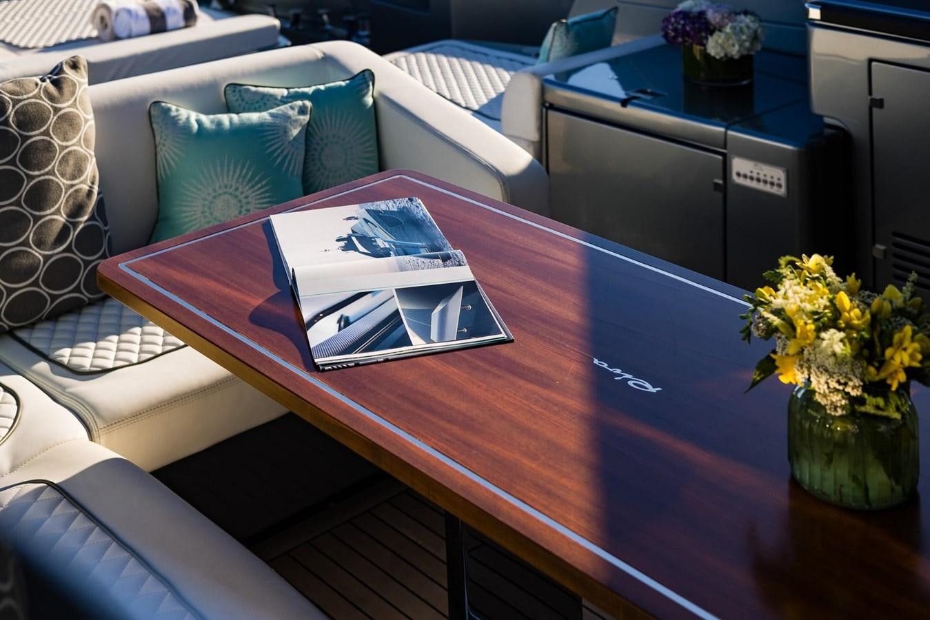 a table with a laptop and a book on it aboard 2021 RIVA 76' BAHAMAS Yacht for Sale