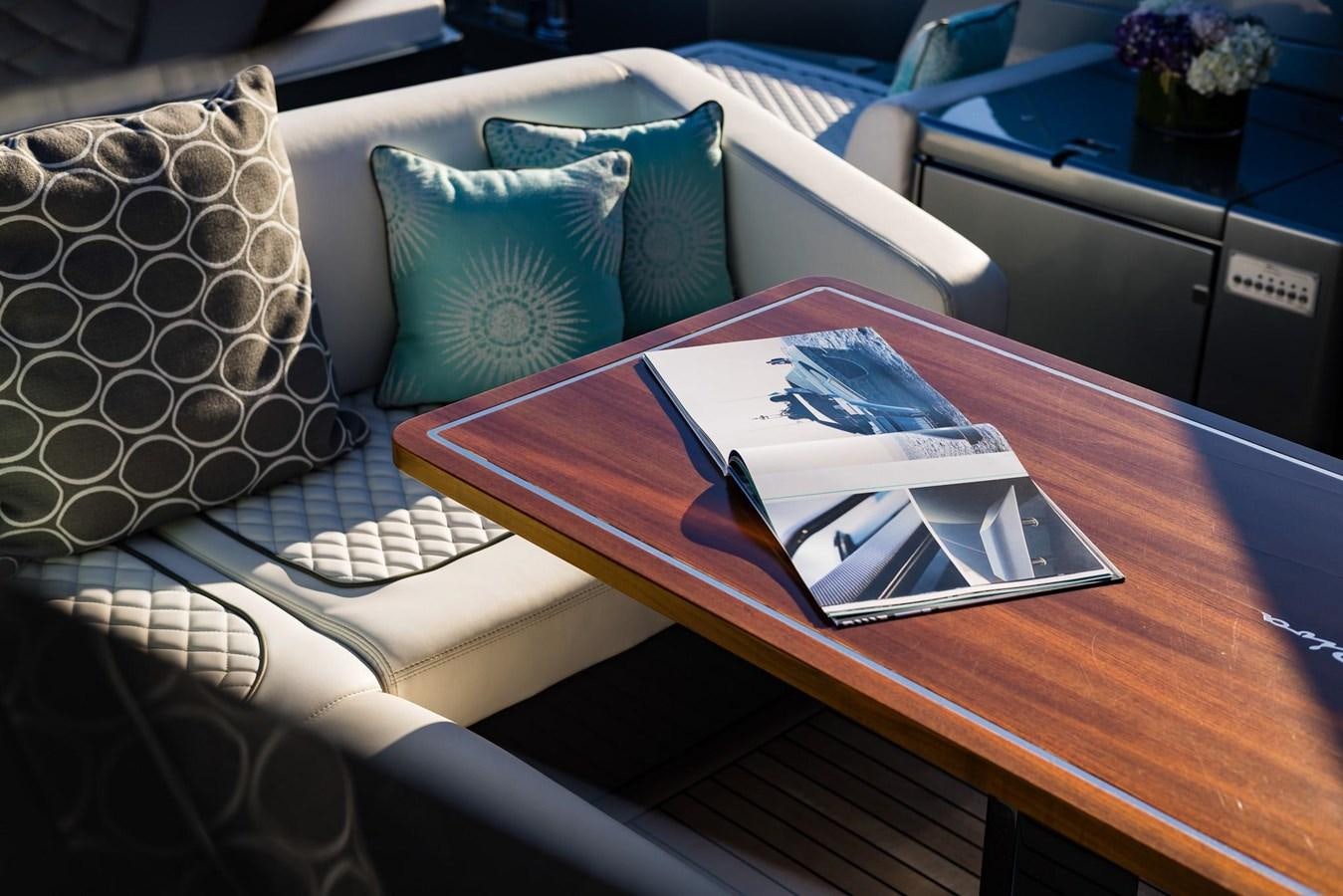 a table with a book and pen on it aboard 2021 RIVA 76' BAHAMAS Yacht for Sale