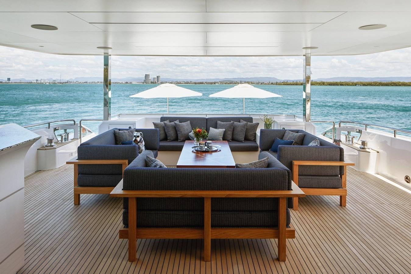 a couch and a table on a deck overlooking a beach aboard ASKARI Yacht for Sale