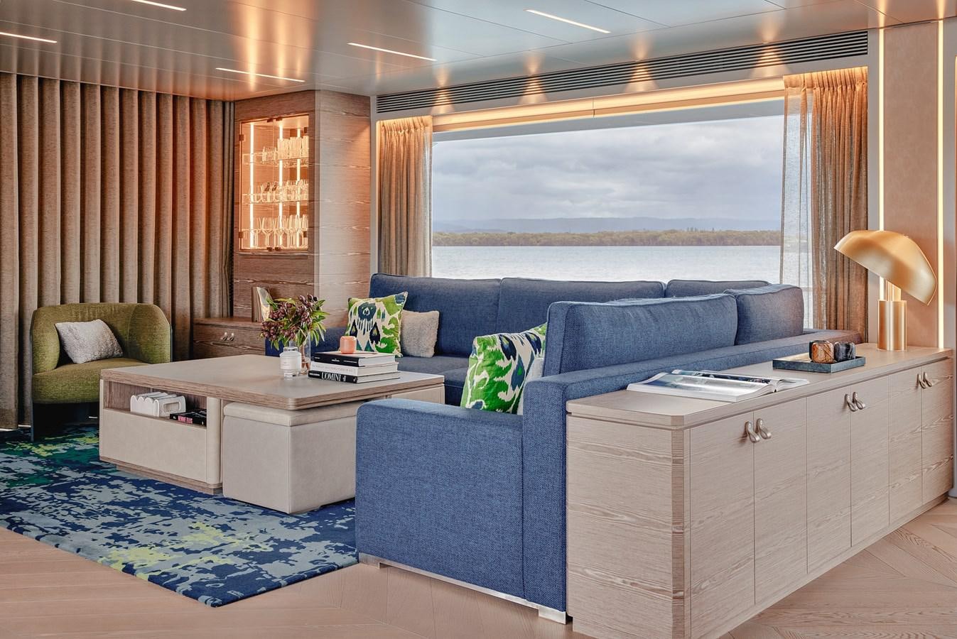a living room with a blue couch and a white table aboard ASKARI Yacht for Sale