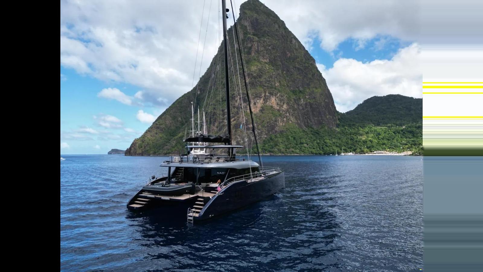 a boat on the water with Pitons in the background aboard NAOMA Yacht for Sale