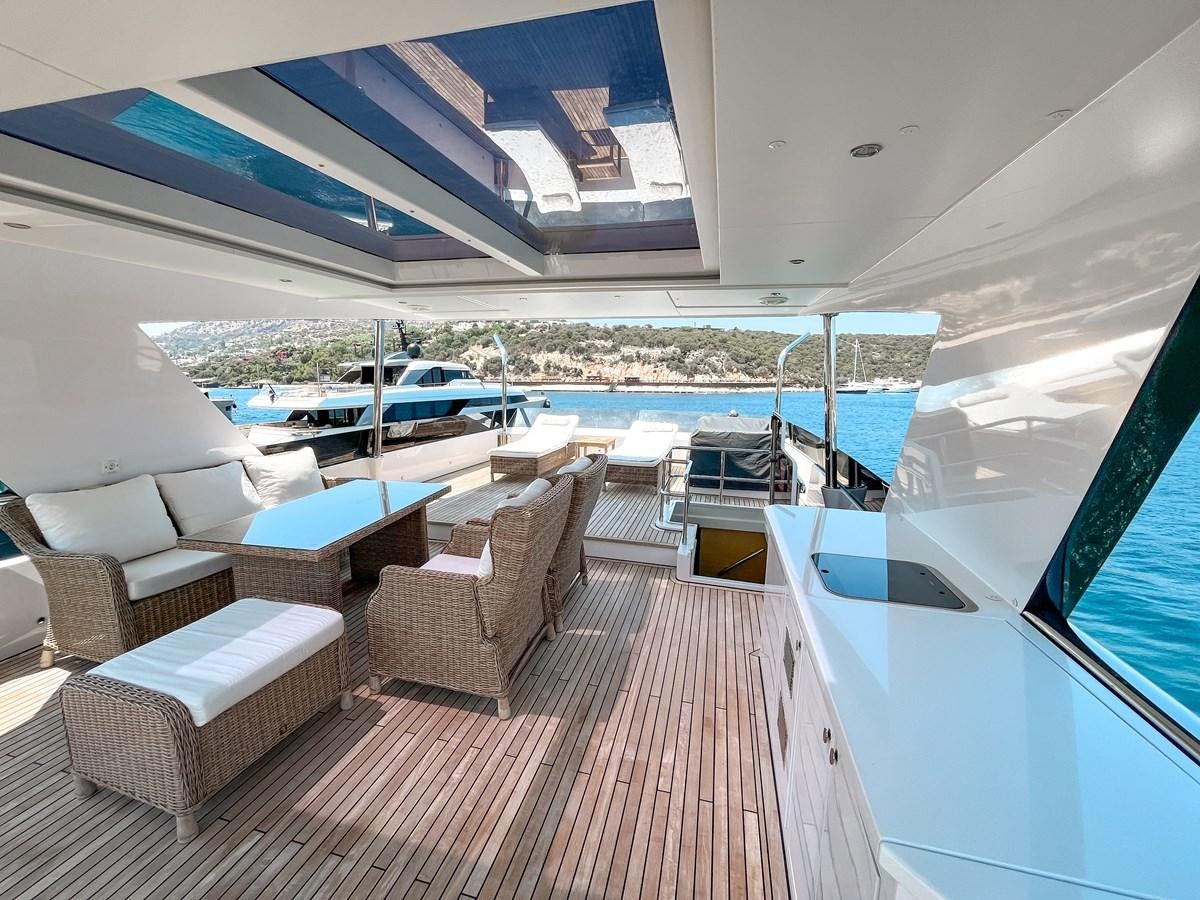 a room with a deck and chairs aboard SAADET SULTAN Yacht for Sale