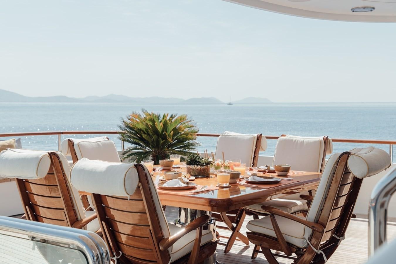 a table set for a meal on a balcony overlooking the ocean aboard HERCULES Yacht for Sale