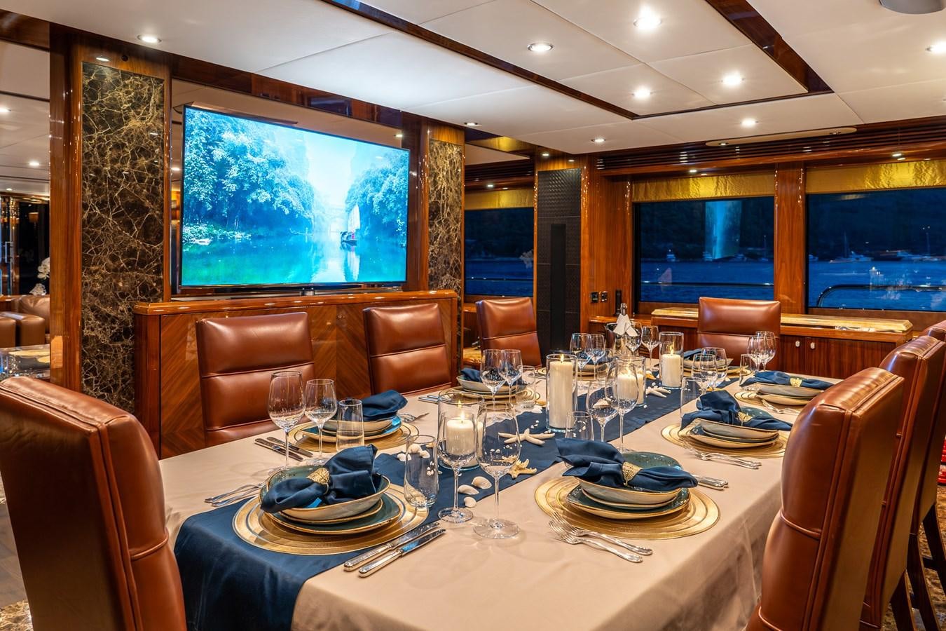 a large dining room with a large table set for dinner aboard IMAN Yacht for Sale