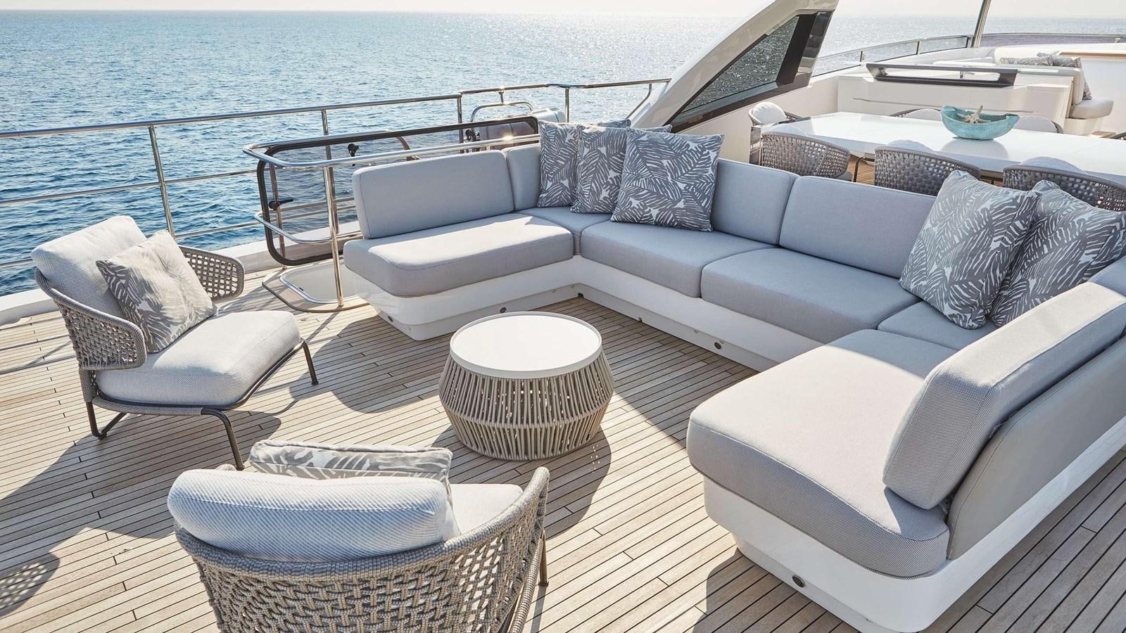 a couch and a table on a deck overlooking a body of water aboard GHOST Yacht for Sale