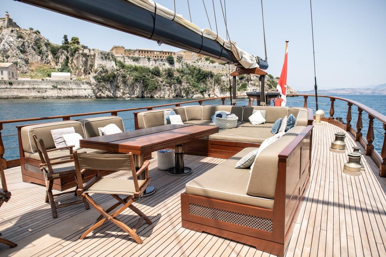 a deck with chairs and tables on it by a body of water aboard CASSIOPEIA Yacht for Sale