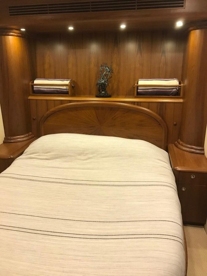 a bed with a white sheet and a bookcase aboard IN FLIGHT Yacht for Sale