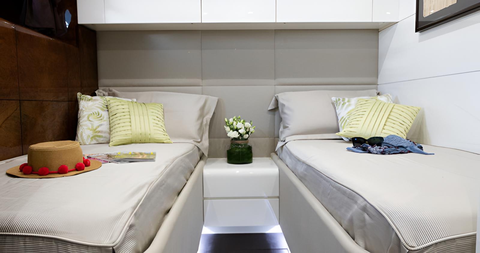 a couple of beds next to each other with white pillows and flowers aboard CAMILLA A Yacht for Sale