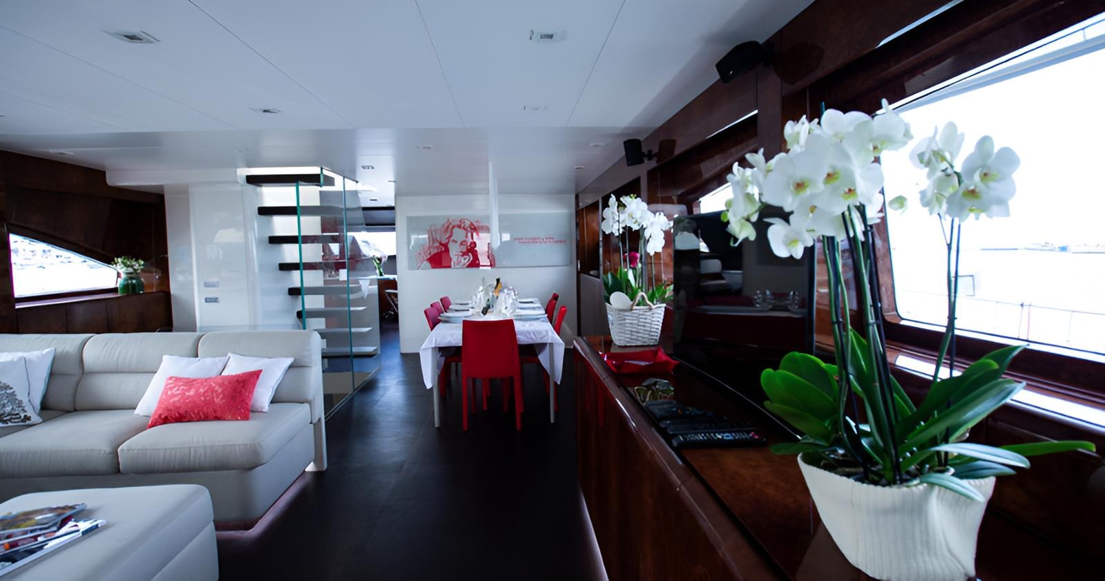 a living room with a white couch and a table with flowers aboard CAMILLA A Yacht for Sale