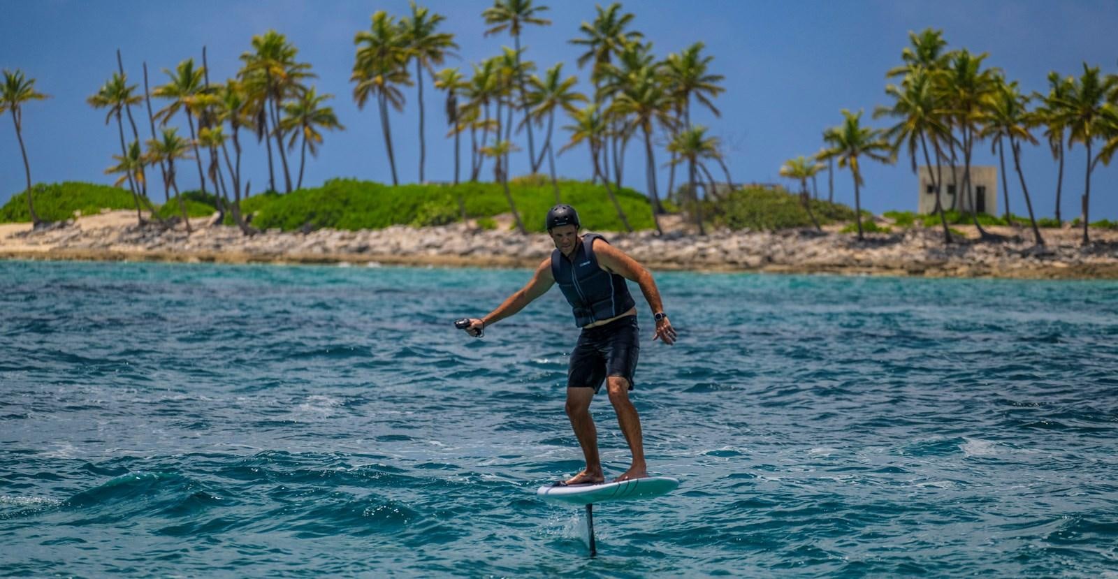 a man riding a surfboard aboard BG CHARADE Yacht for Sale