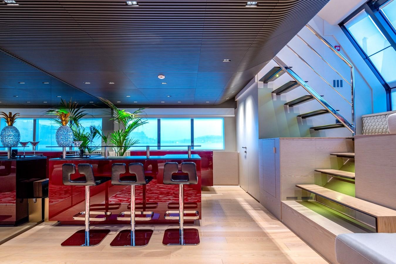 a room with a staircase and red chairs aboard HH Yacht for Sale